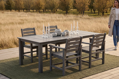 Outdoor dining set with table and chairs on a wooden deck, woman walking in the background.