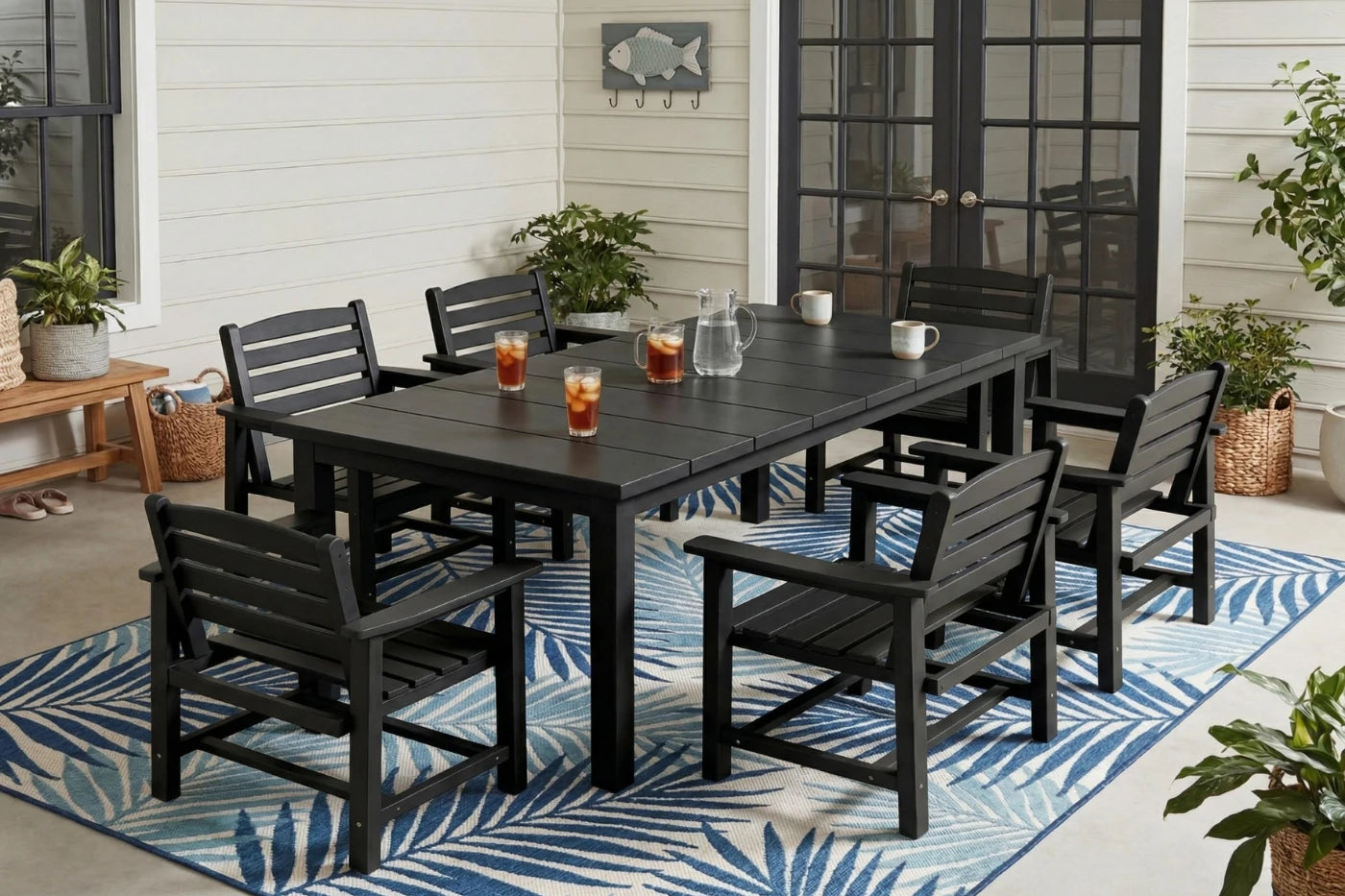 Outdoor dining set with black table and chairs on a patio with a blue and white patterned rug.