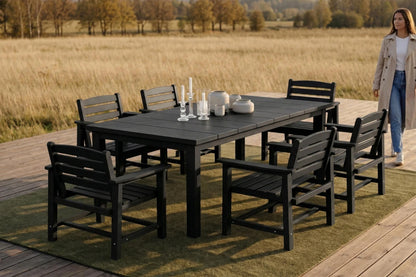 Outdoor dining set with table and chairs on a wooden deck overlooking a field.