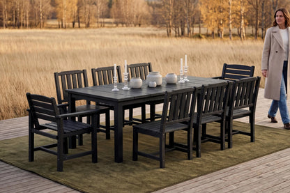 Outdoor dining set with table and chairs on a wooden deck by a field