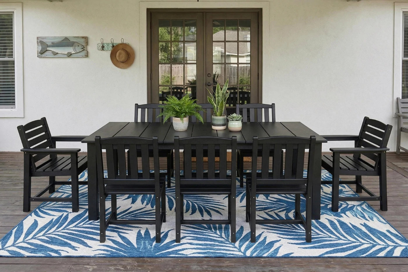 Outdoor dining set with black table and chairs on a blue and white patterned rug.