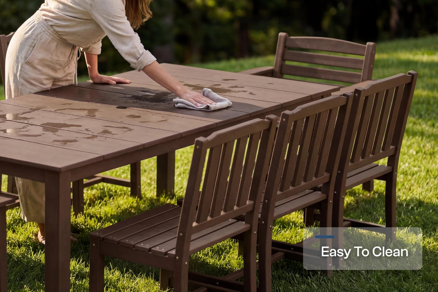 Person cleaning an outdoor table with chairs on a grassy area, emphasizing ease of cleaning.