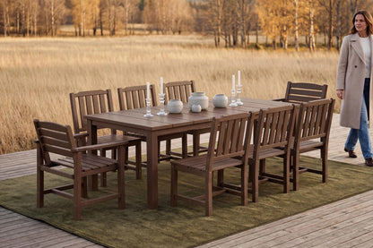HDPE outdoor dining set with chairs and a table on a deck, with a person walking in the background.