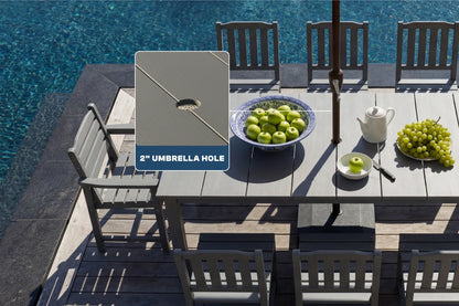 Outdoor dining table with chairs by a pool, featuring an umbrella hole cover.