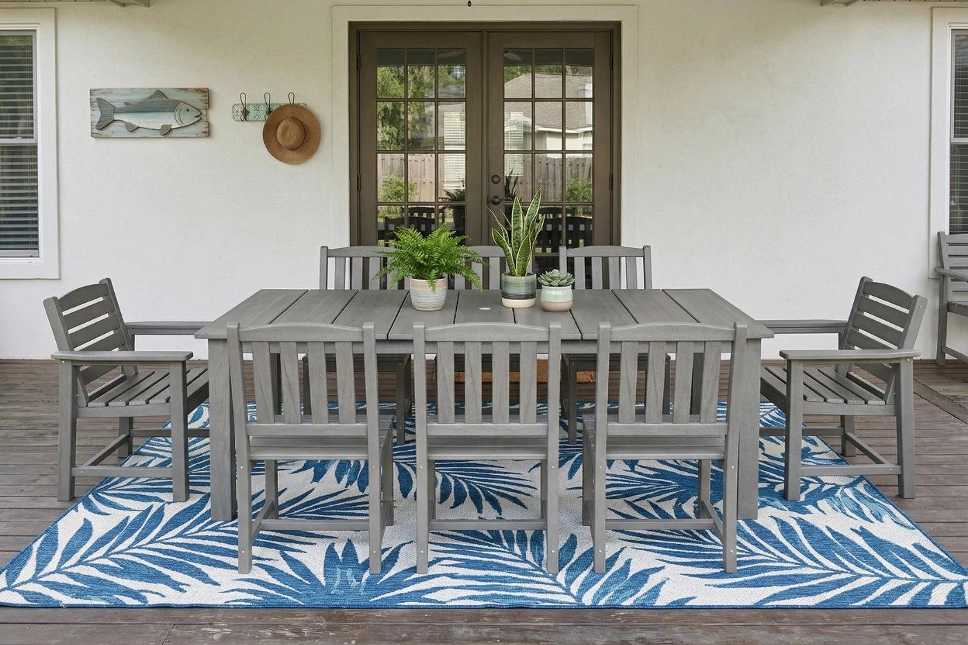Outdoor dining set with gray table and chairs on a blue and white patterned rug.