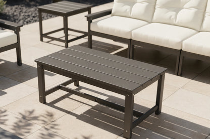 Outdoor patio set with a coffee table and sofa on a tiled patio.
