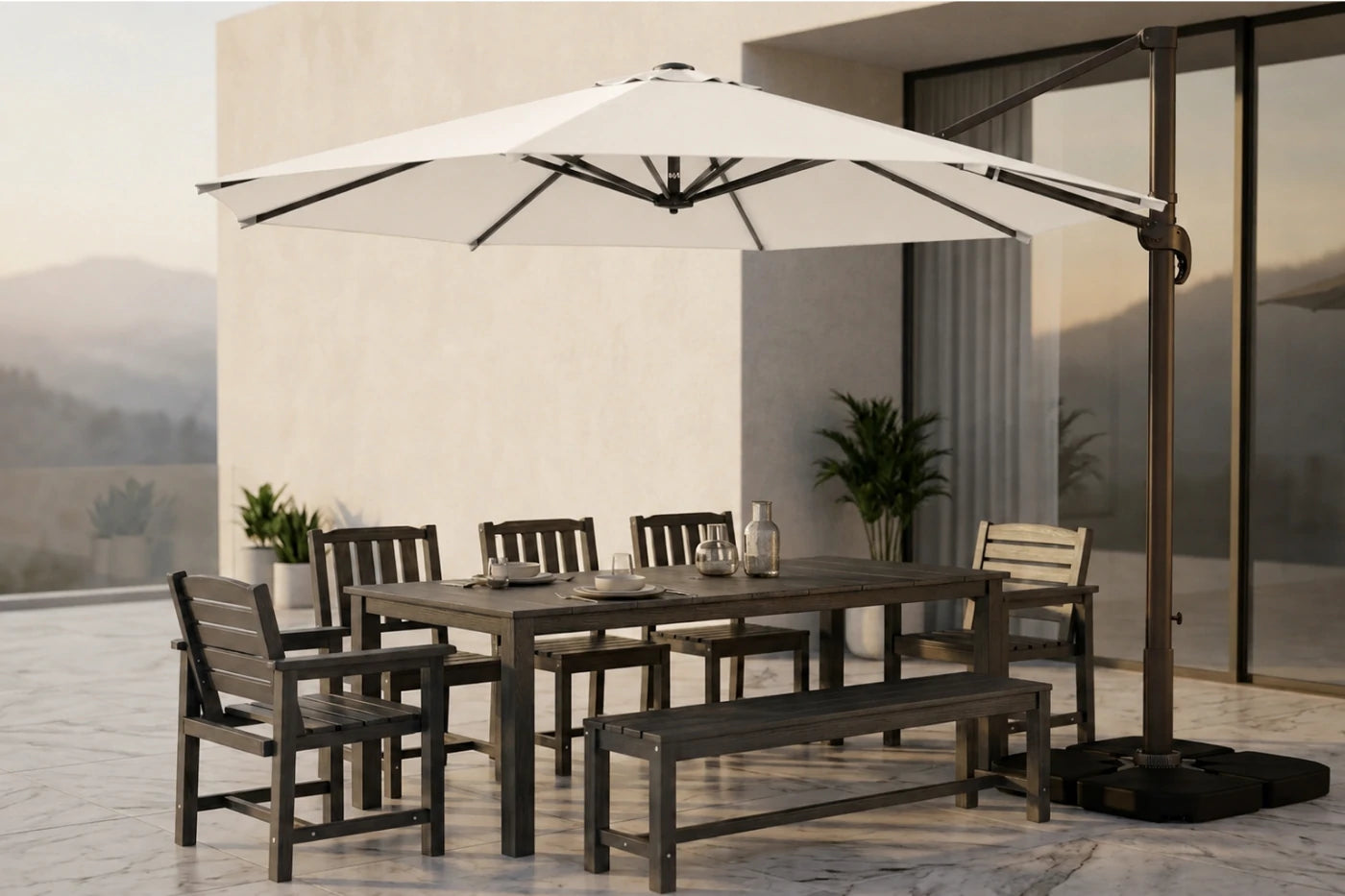 Outdoor patio dining set with a rectangular dark table, matching chairs and bench, and a large white cantilever umbrella on a tiled terrace beside a modern building.