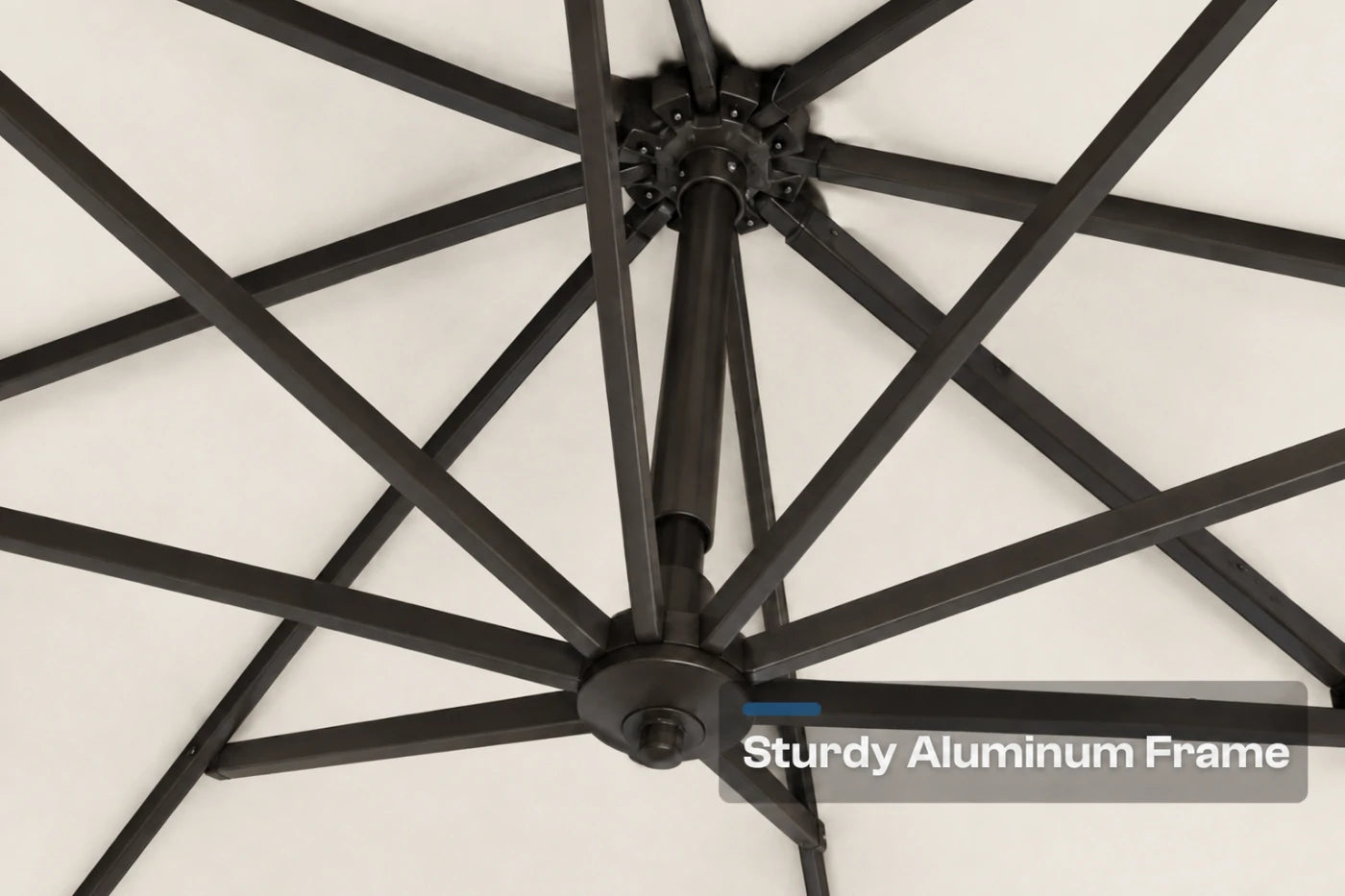 Close-up of a black aluminum patio umbrella frame with radiating ribs against a creamy white canopy background, with a text overlay reading 'Sturdy Aluminum Frame'.