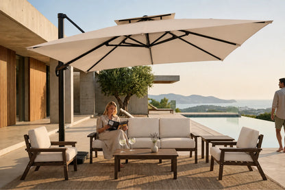 Outdoor patio furniture set with a large beige cantilever umbrella, a beige sofa, two matching armchairs, and a low wooden coffee table, shown in a luxurious modern villa setting with a pool and a woman sitting on the sofa.