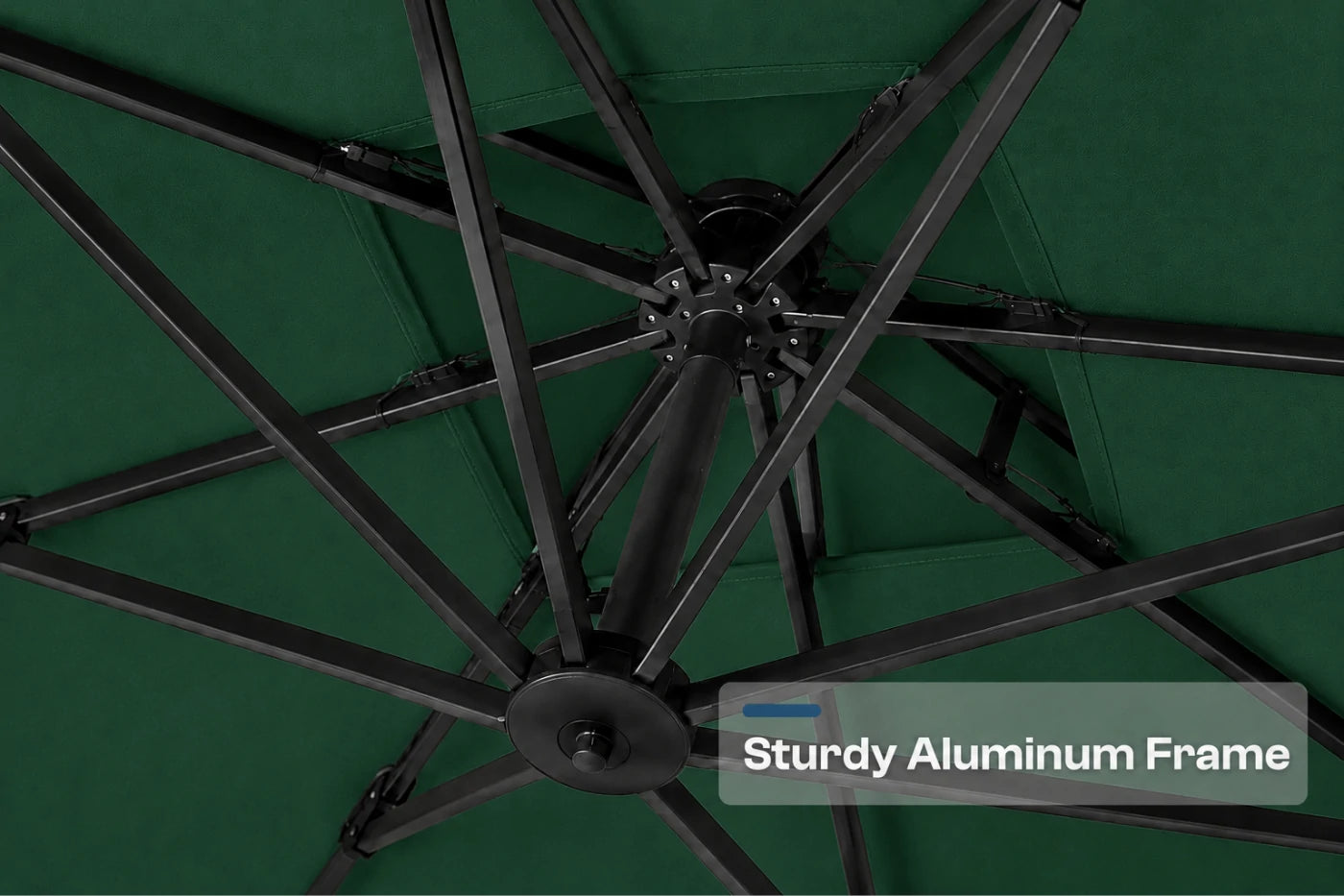 Close-up of the underside of a patio umbrella showing a dark green canopy and a black aluminum frame with radiating ribs. A text overlay reads 'Sturdy Aluminum Frame'.