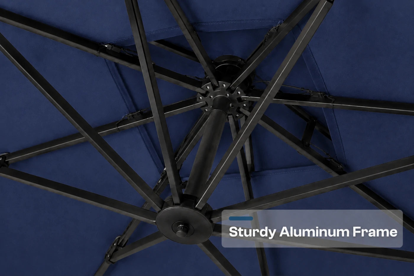 Close-up of the underside of a navy blue patio umbrella canopy showing the radial aluminum frame structure, with a text overlay that reads 'Sturdy Aluminum Frame'.