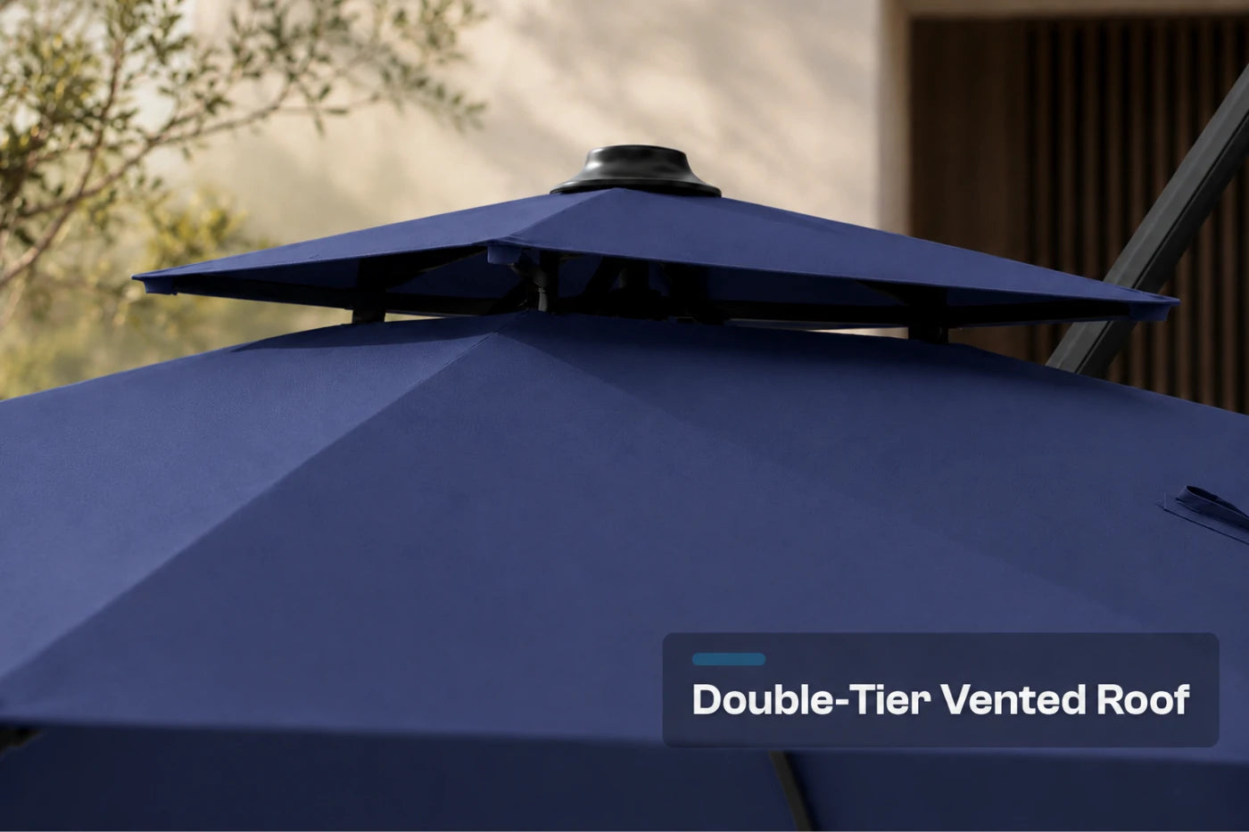 Close-up of a navy blue patio umbrella showing the double-tiered roof structure with a text overlay that reads 'Double-Tier Vented Roof'.