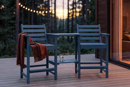 Two blue chairs with a small table on a wooden deck during sunset.
