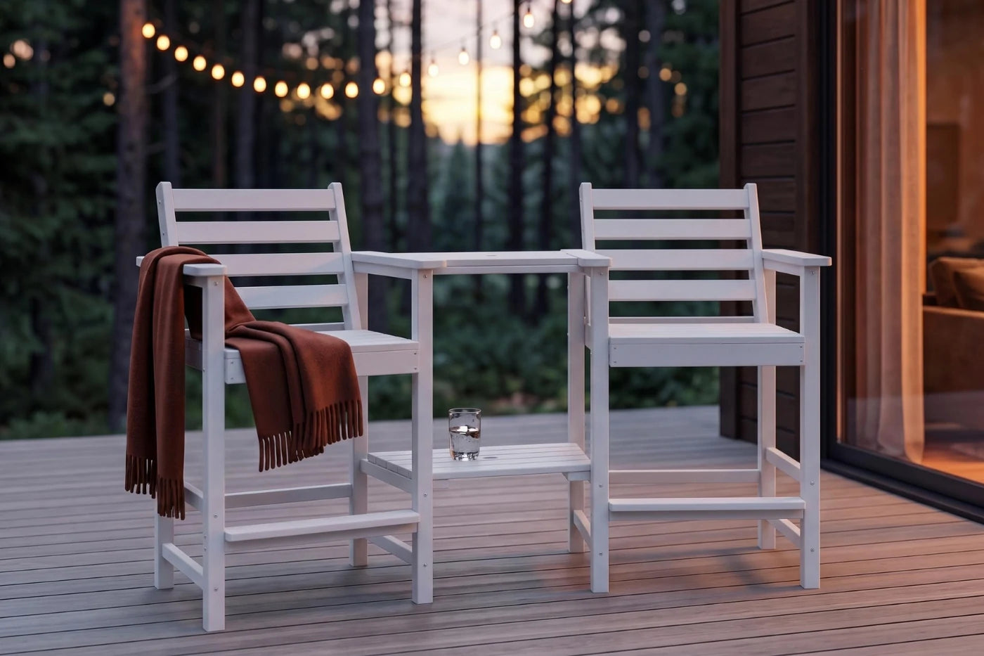 Two white chairs with a brown blanket on a wooden deck at sunset.