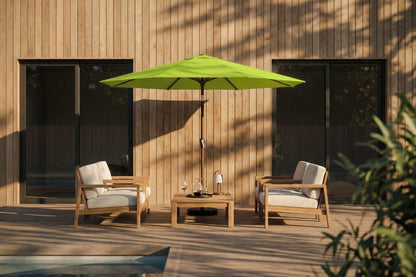 Outdoor patio set with two chairs and a table under a green umbrella against a wooden wall.