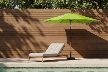 Green patio umbrella and lounge chair by a poolside with wooden wall background