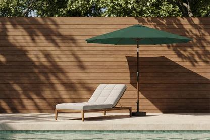 Chaise lounge with green umbrella by a poolside against a wooden wall