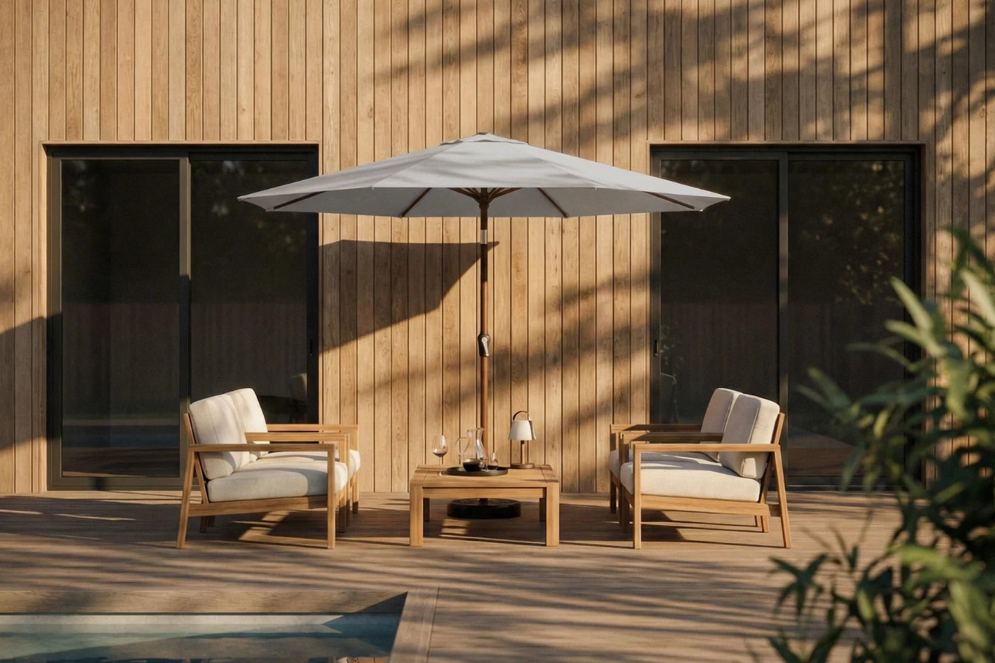 Outdoor patio set with two chairs, a table, and an umbrella against a wooden wall.