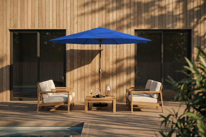 Outdoor patio set with two chairs and a table under a blue umbrella against a wooden wall.