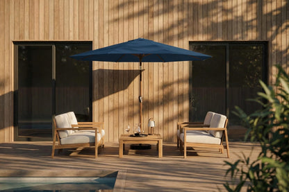 Outdoor patio set with two chairs, a table, and a blue umbrella against a wooden wall.
