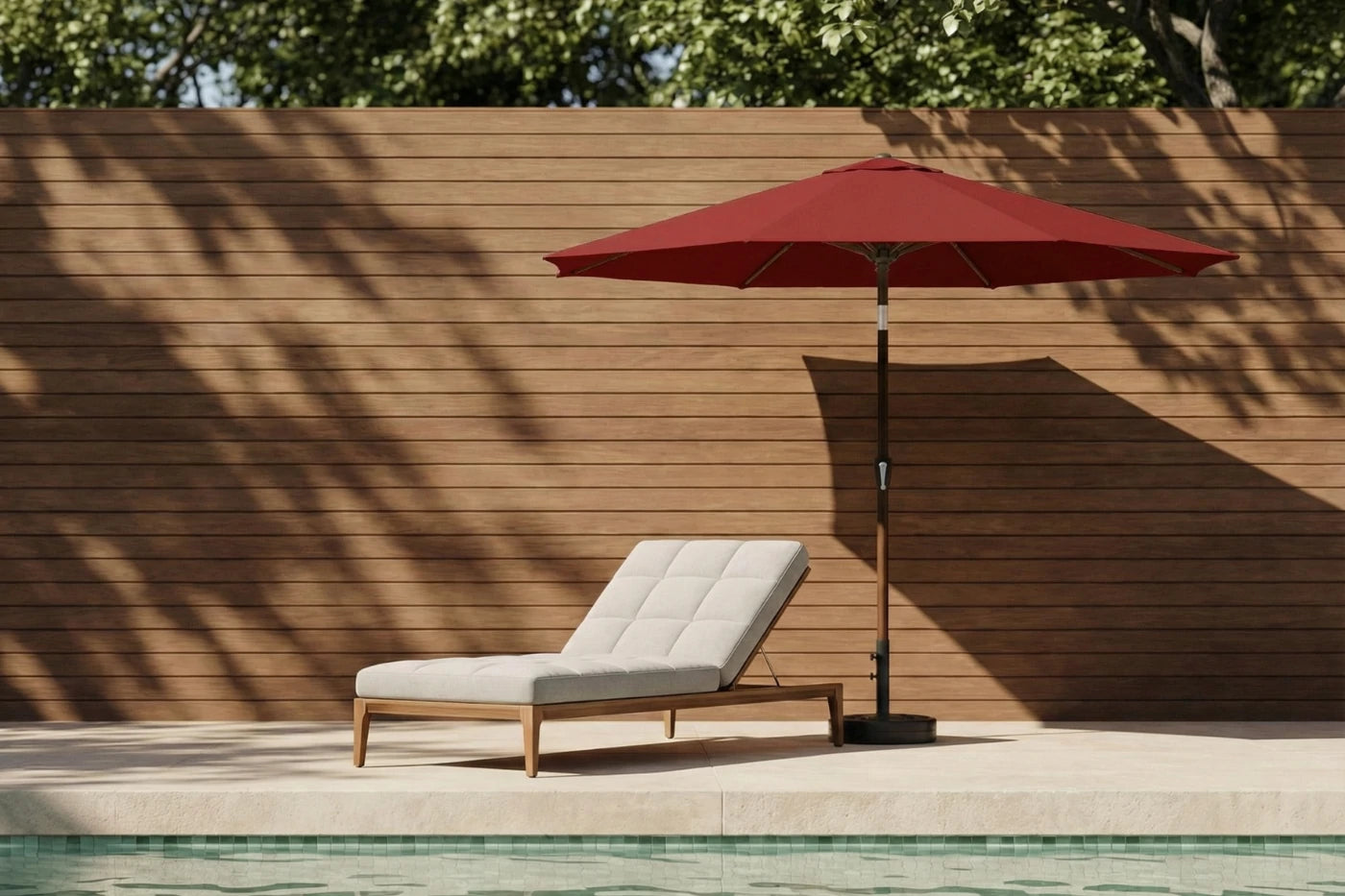 Red patio umbrella and lounge chair by a poolside with wooden wall background