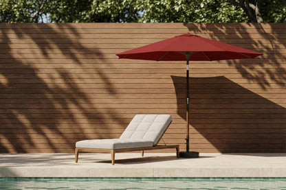 Red patio umbrella and lounge chair by a poolside with wooden wall background