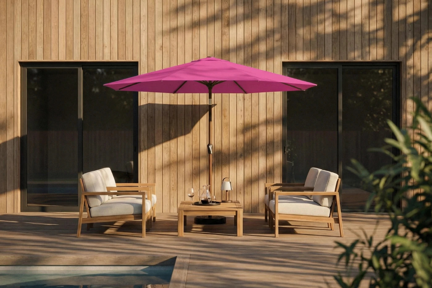 Outdoor patio set with pink umbrella, chairs, and table against a wooden wall.