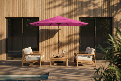 Outdoor patio set with pink umbrella, chairs, and table against a wooden wall.