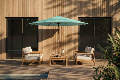 Outdoor patio set with two chairs, a table, and a green umbrella against a wooden wall.