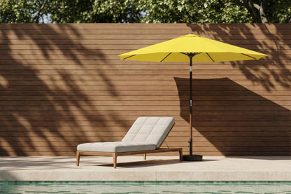 Yellow patio umbrella and lounge chair by a poolside with wooden wall background