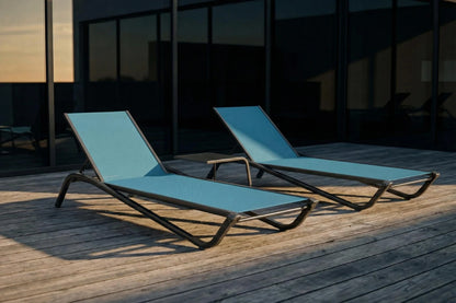 Two blue lounge chairs on a wooden deck with a building in the background.