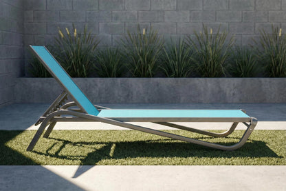 Blue lounge chair on grass with a stone wall and plants in the background