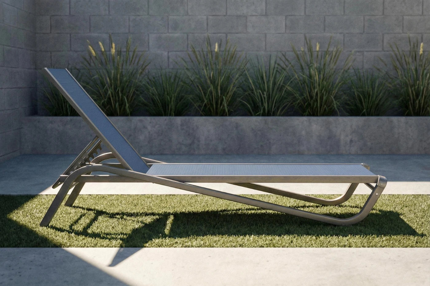 Modern outdoor lounge chair on grass with a stone wall and plants in the background