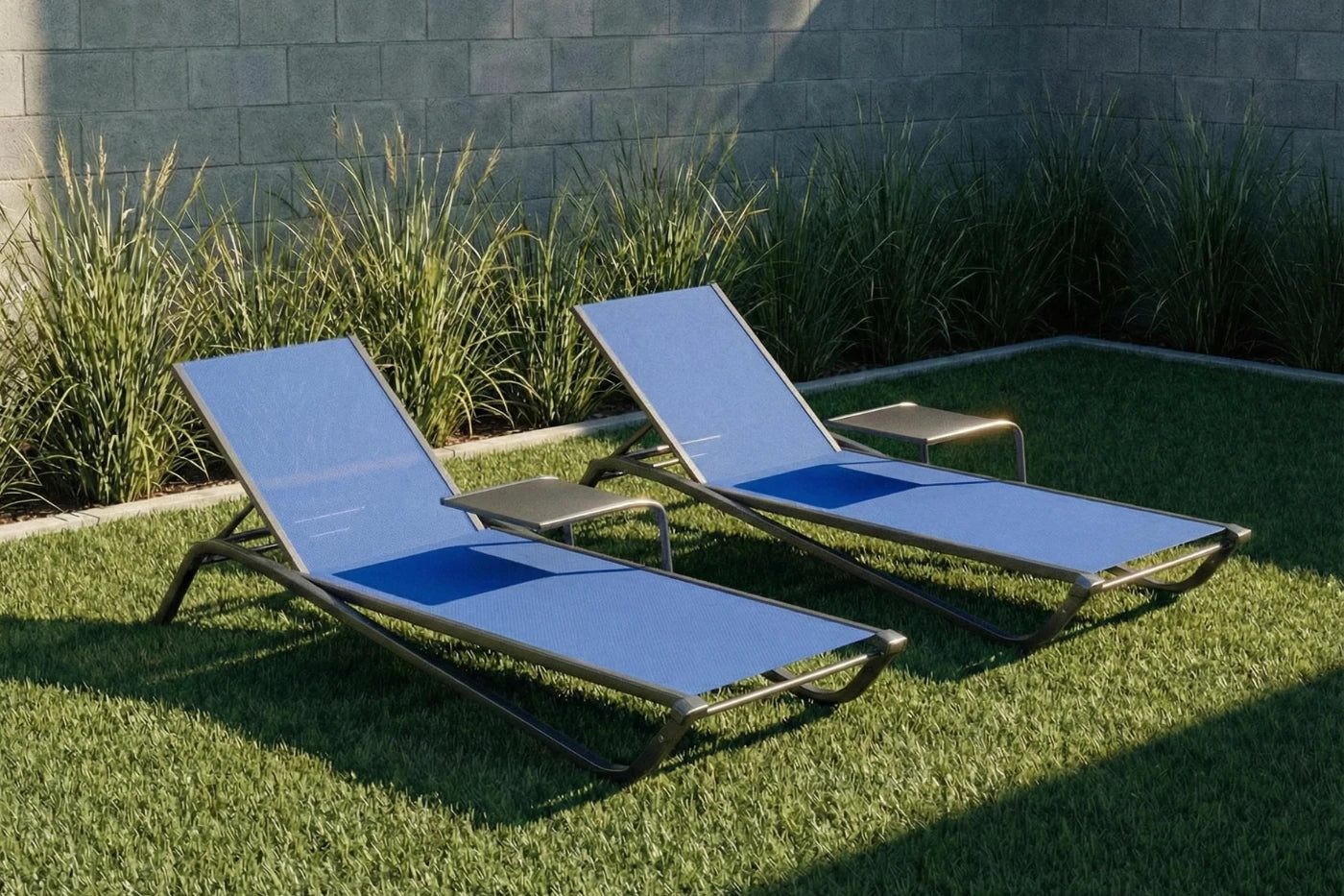 Two blue lounge chairs on grass with a stone wall and plants in the background
