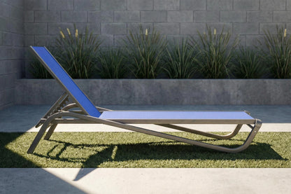 Blue lounge chair on grass with a pool and brick wall in the background