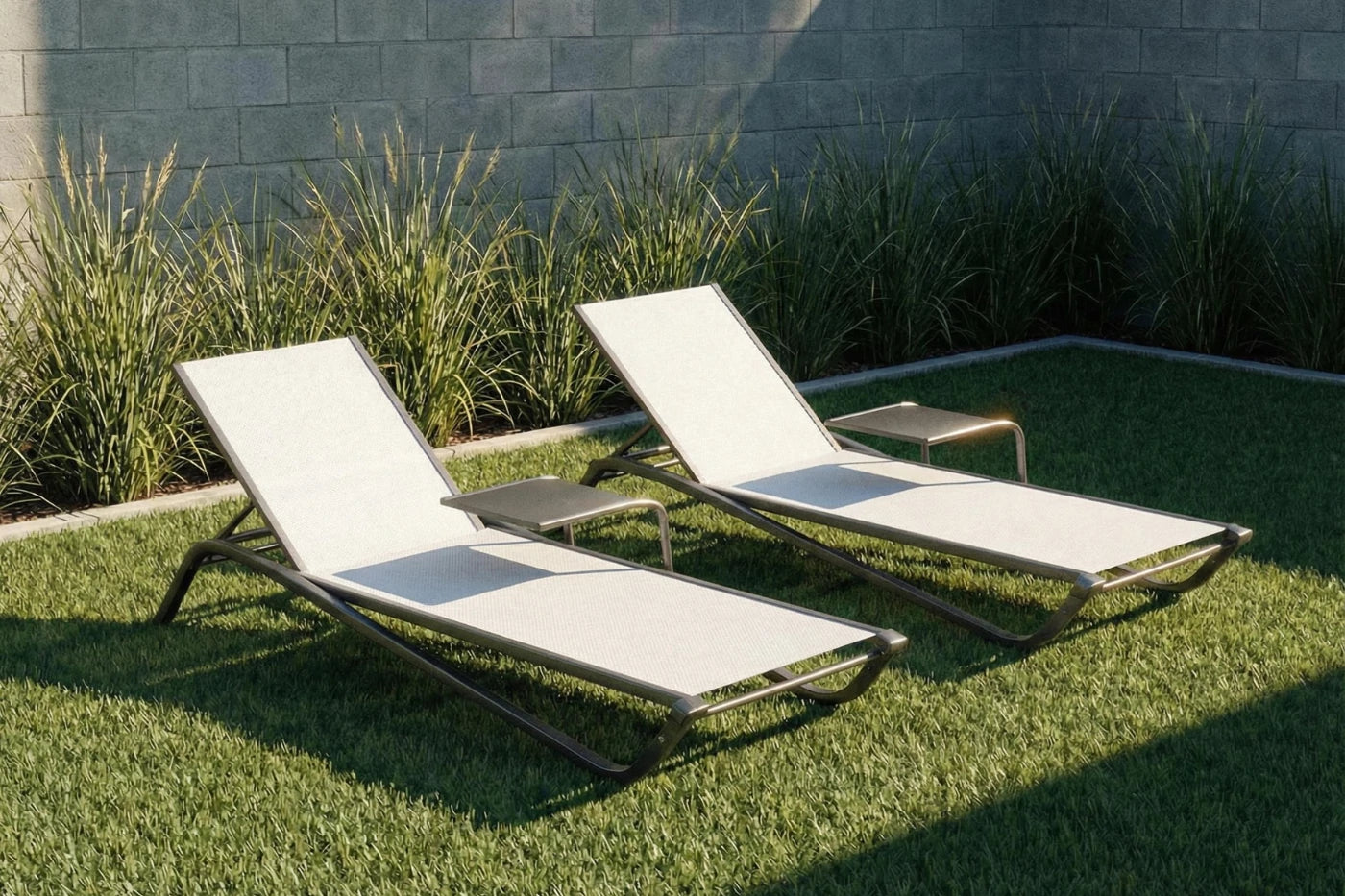 Two white lounge chairs on a grassy area with a stone wall in the background