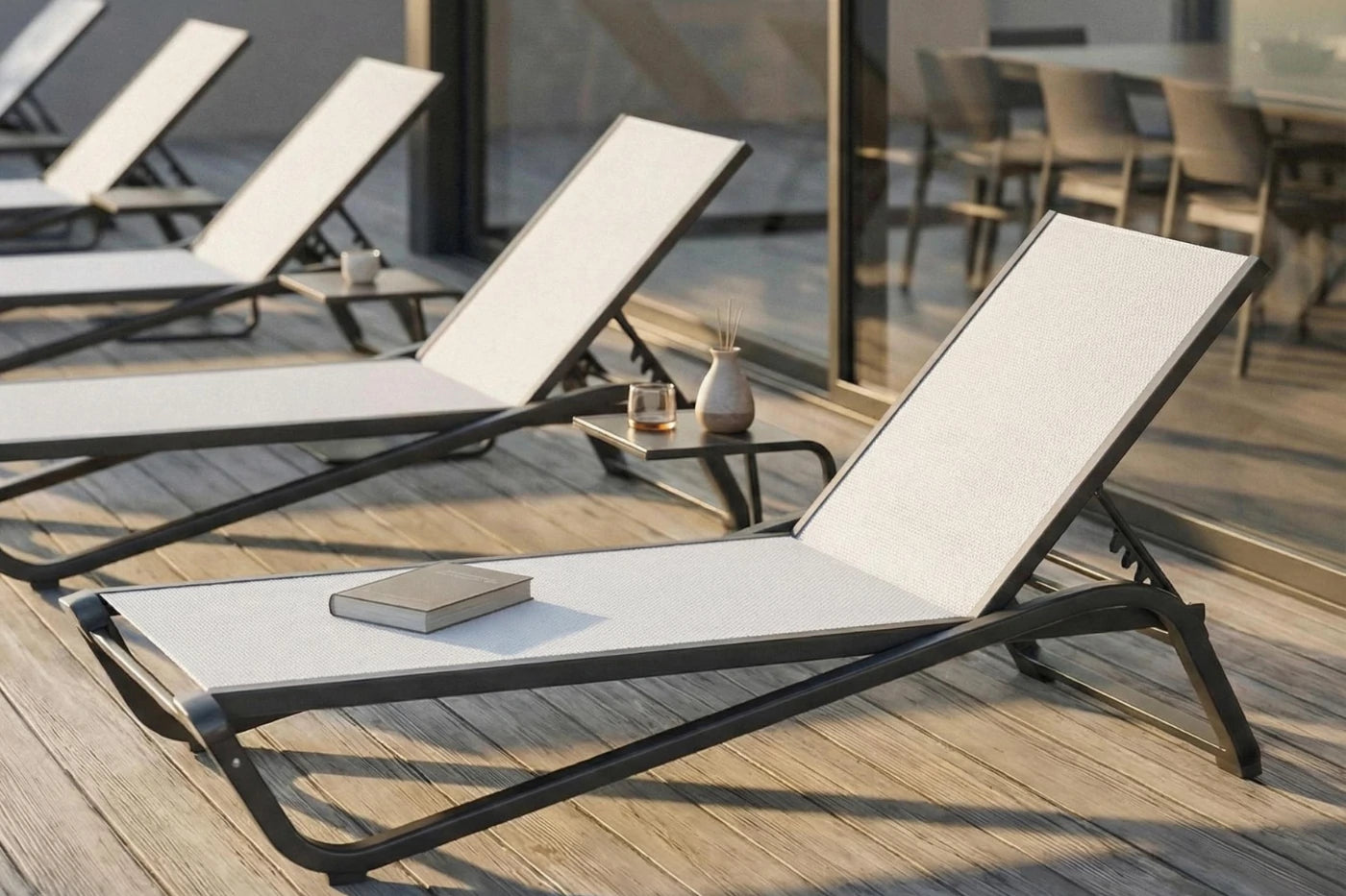 Modern lounge chairs on a wooden deck with a book and small plant.