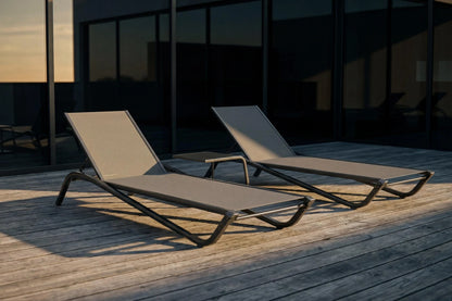 Two lounge chairs on a wooden deck with a building in the background