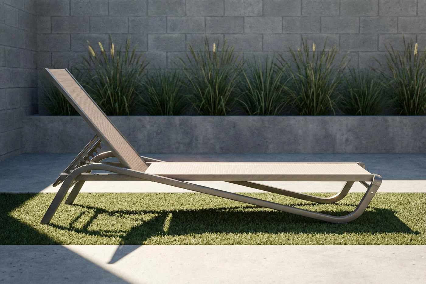 Modern outdoor lounge chair on grass with a stone wall and plants in the background