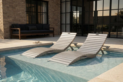 Two lounge chairs by a poolside with a modern building in the background