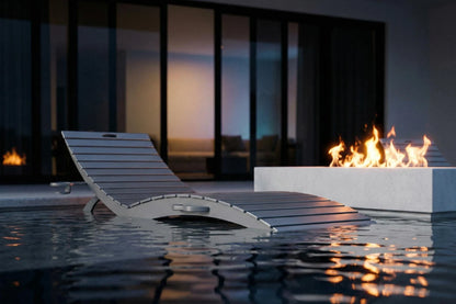 Modern lounge chair by a pool with a fire pit in the background