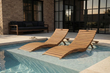 Two wooden lounge chairs by a pool with a building in the background