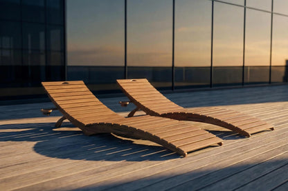 Two wooden lounge chairs on a rooftop deck with a cityscape background.