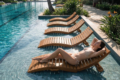 Woman relaxing on a wooden lounge chair by a pool