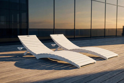 Two white lounge chairs on a wooden deck with a modern building in the background.