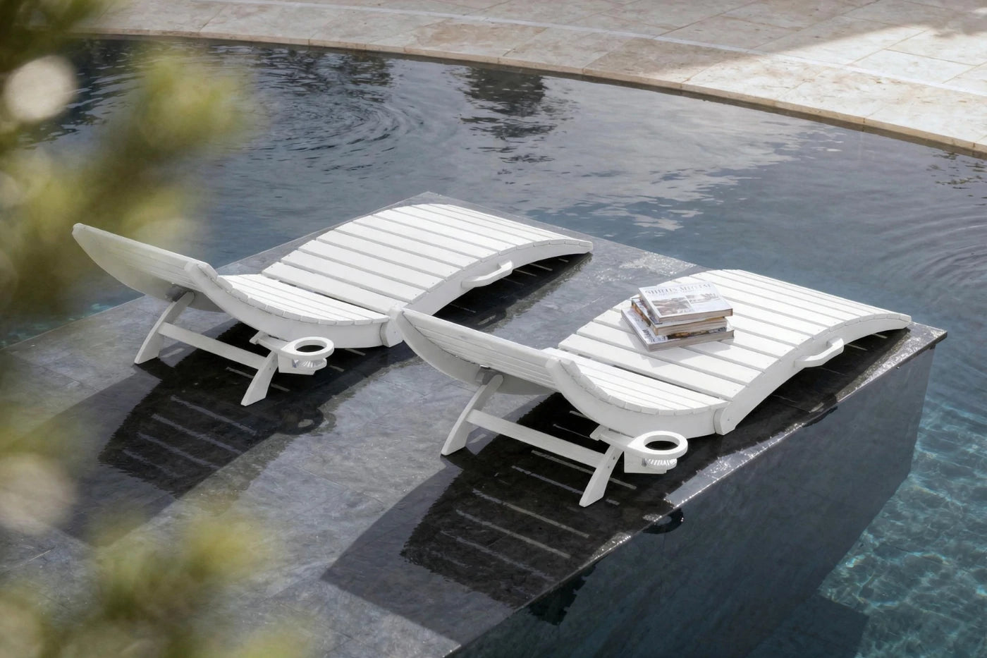 Two white lounge chairs on a platform over water
