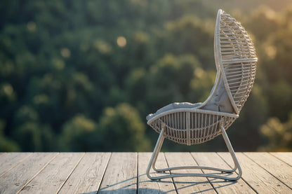 Wicker chair on a wooden deck with a blurred natural background