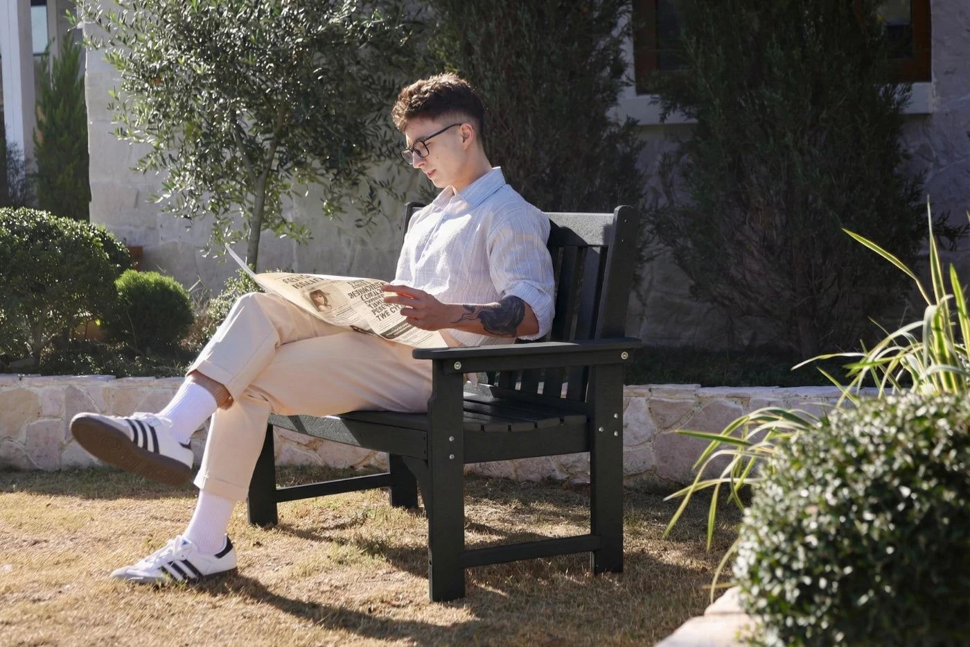 Man reading a newspaper on a bench outdoors