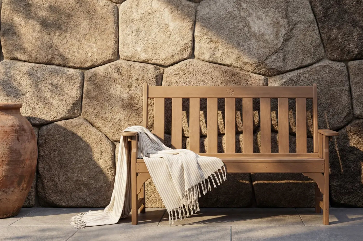 Wooden bench with a blanket against a stone wall