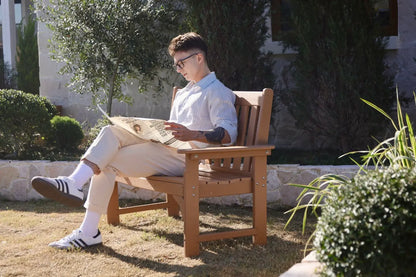 Man sitting on a wooden bench reading a newspaper in a garden.